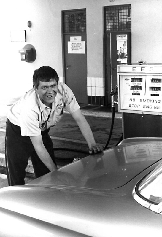 Historic black-and-white photo of an Exchange employee fueling a car at a service station