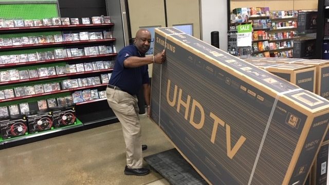 Tyrone Jones, retail management trainee, lifts a large UHD TV at the Barksdale Exchange.