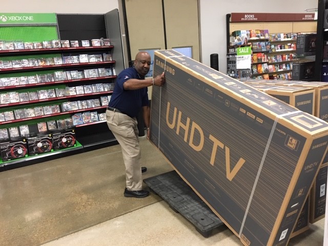 Tyrone Jones, retail management trainee, lifts a large UHD TV at the Barksdale Exchange. 