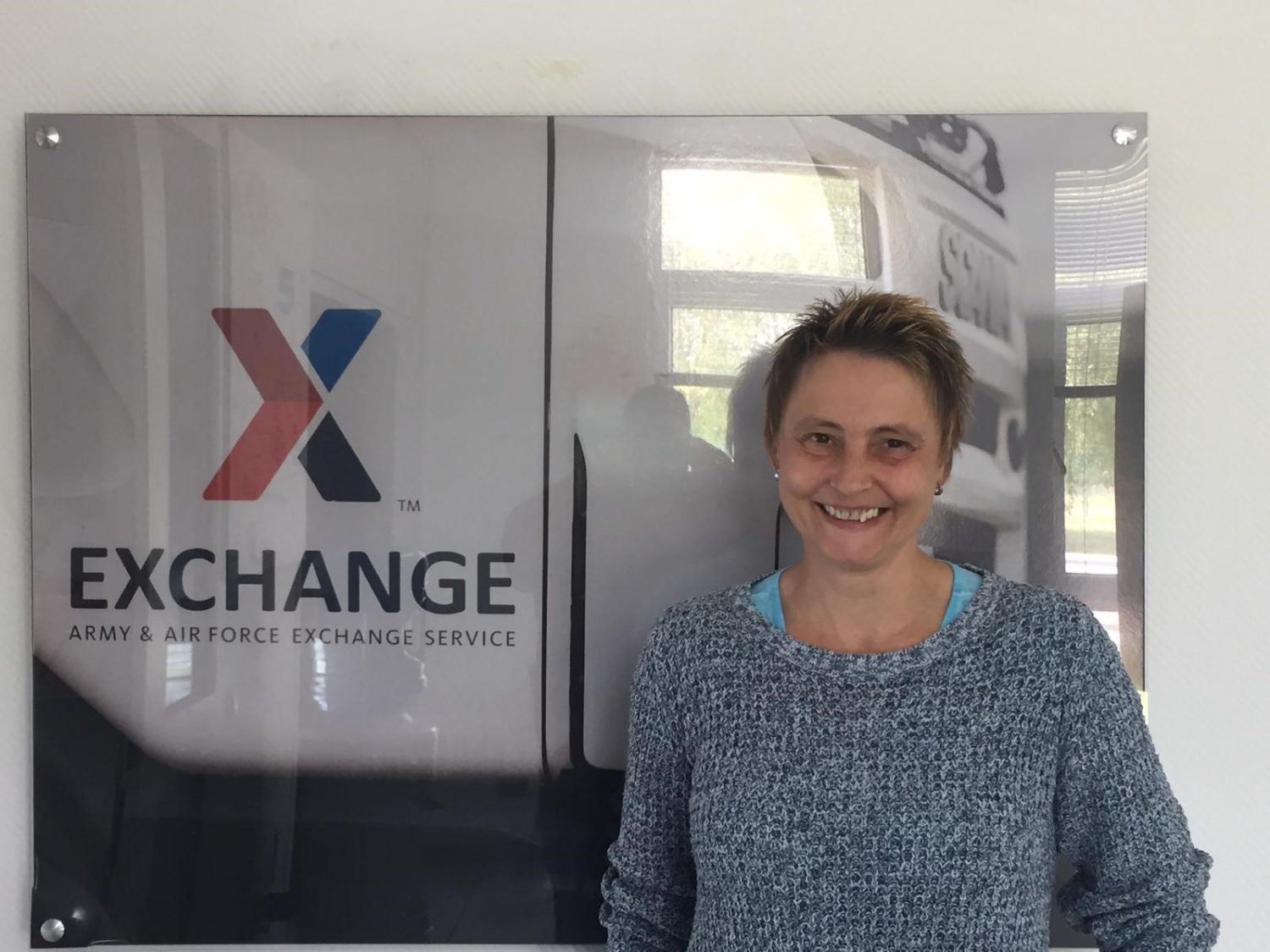 Heike Molter stands in front of a glass wall with the Exchange logo in the background