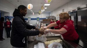 Phillip Jackson, military spouse, receives grab-and-go meals from Sonja Gates, Department of Defense Education Activity school meal program manager at Ramstein Air Base, Germany, March 25, 2020, as children attended school from home. (Airman 1st Class Jennifer Gonzales/Air Force)