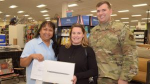 Air Force Master Sgt. Brett Myers, Engineering Craftsman with the 718th Civil Engineer Squadron, and his wife, Misti, pose for a picture with Flor Payton, Kadena Exchange main store manager, after Brett surprised Misti with a MacBook Pro. Brett used the Exchange’s layaway program for the first time to purchase the laptop for Misti, who is pursuing a degree in medical administration. On Dec. 15, Brett was invited to a video call with celebrity and Marine and Navy Veteran, Montel Williams. During the call, Williams announced that all Exchange layaways in the Pacific Region, including Brett’s, were paid in full by nonprofit Pay Away the Layaway. (U.S. Army Photo by Staff Sgt. Mark A. Kauffman)