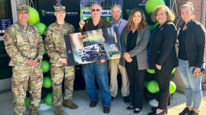 Sweepstakes winner poses with a sign with representatives from the Fort Belvoir Exchange and military leadership.