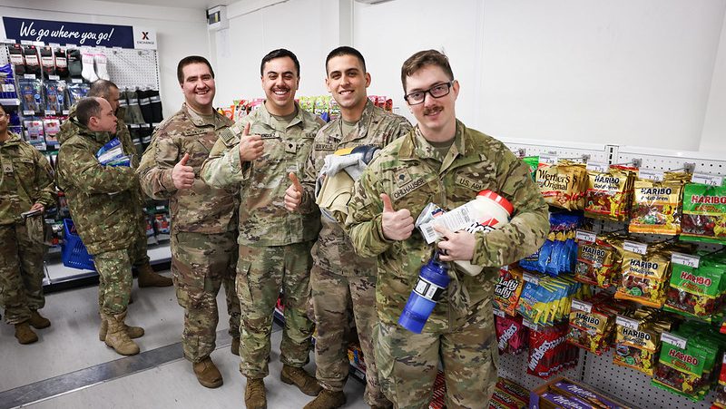 Soldiers holding snacks and beverages while giving a thumbs up to the camera